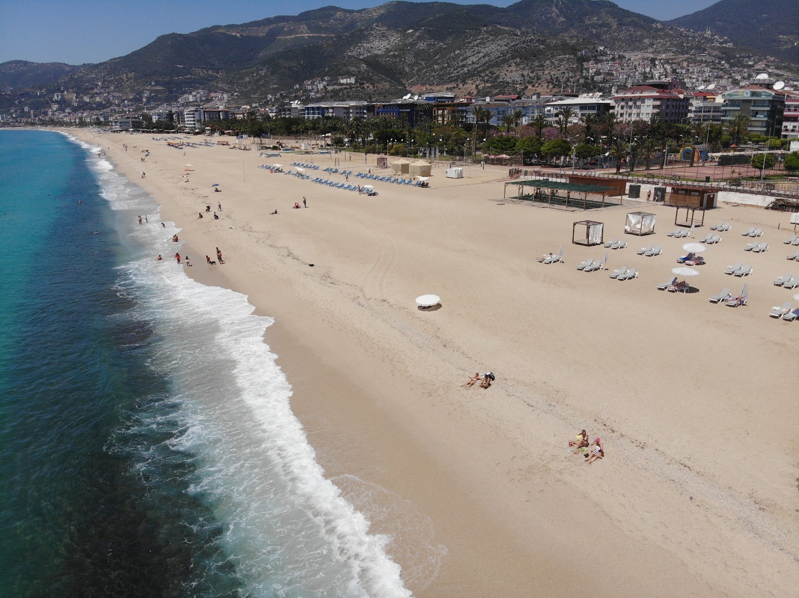 Alanya ilçesinde  kısıtlamadan muaf olan turistler, sıcak havayı fırsat bilerek sahillerde güneşlenip, denize girdi.