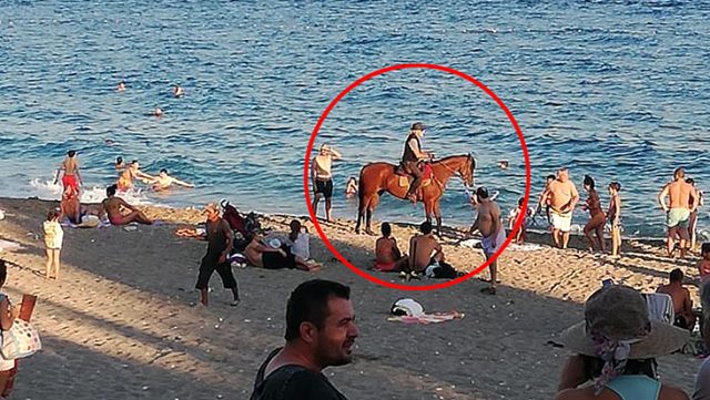 Başında kovboy şapkasıyla atını denize süren gizemli şahıs, görenleri şaşırttı