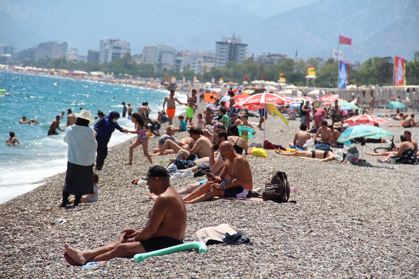 Rüzgara rağmen hava sıcaklığının 30 dereceyi bulduğu turizm kenti Antalya’da sahillerde yoğunluk oluştu