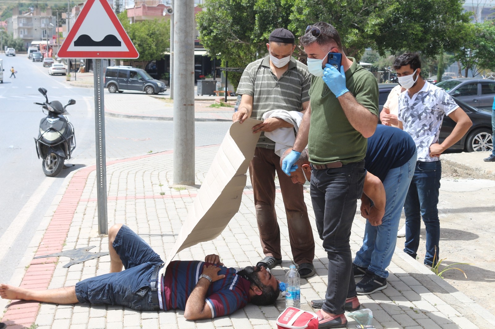 Yaralanan motosiklet sürücüsünü çevredeki vatandaşlar ambulans gelinceye kadar kartonla güneşten korudu.